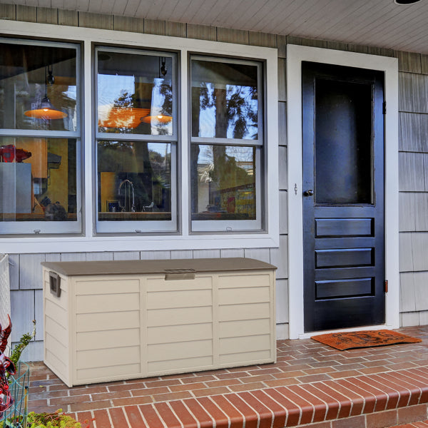 The closed deck box on a brick front porch beside a dark entry door