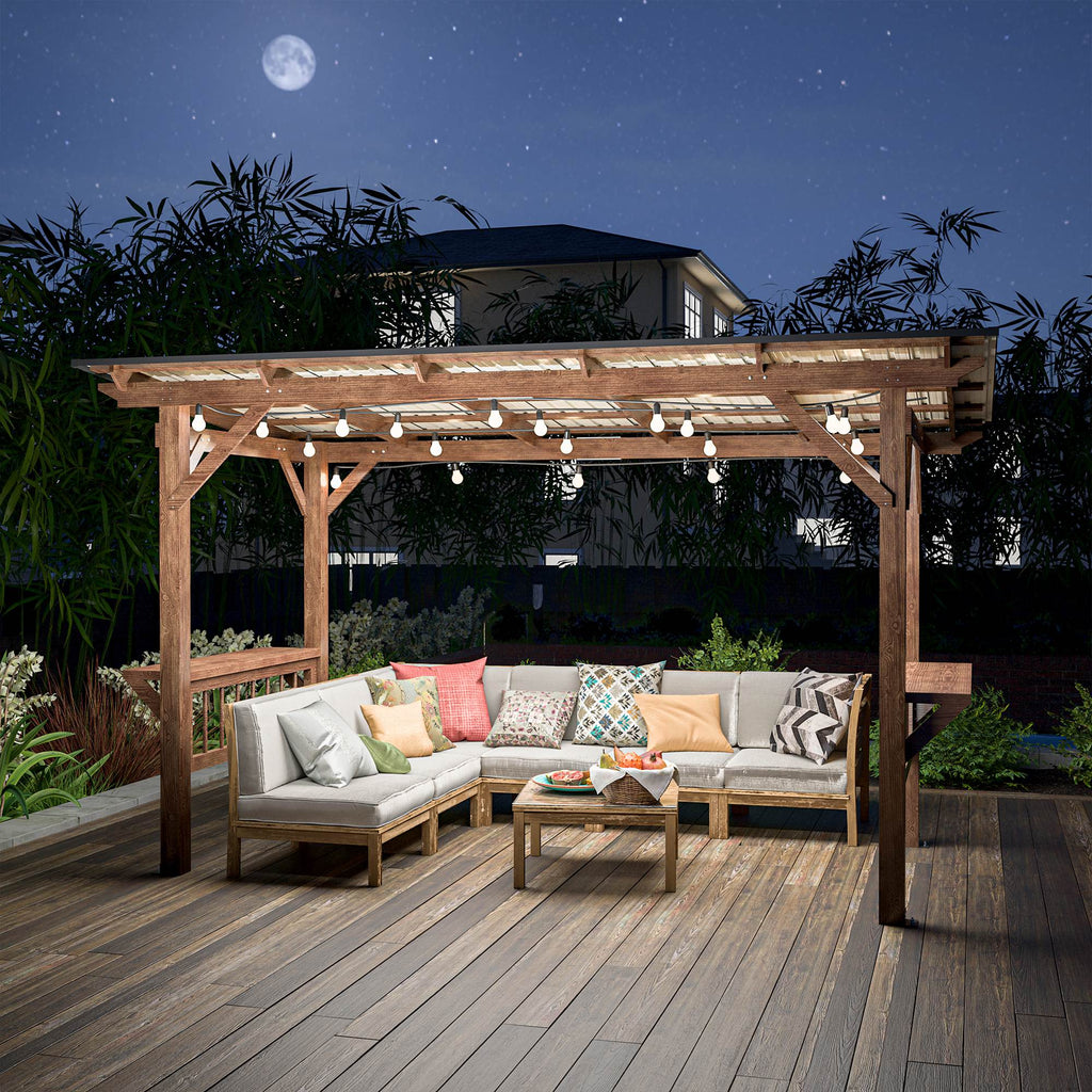 The pergola lit at night over a deck with a sectional sofa beneath it