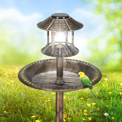 Close view of the lit lamp and wide bronze basin, with a small green and yellow bird perched on the rim against a blue sky