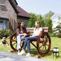 Two people sitting on the carbonized wagon wheel bench on a lawn