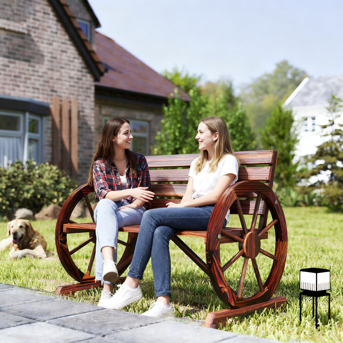 Two people sitting on the carbonized wagon wheel bench on a lawn