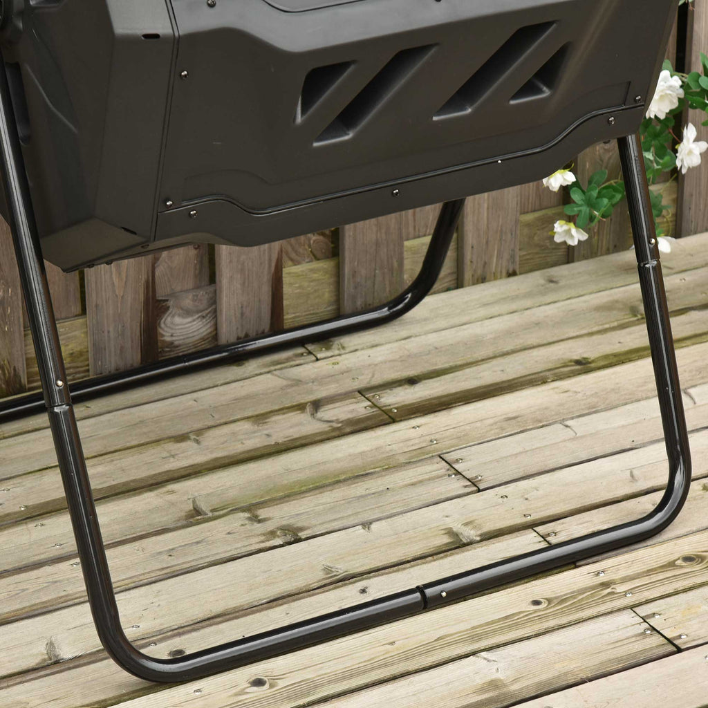 The compost tumbler standing against a wooden fence