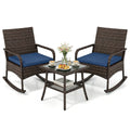 Three-piece brown wicker rocking chair set with navy cushions and two-tier glass side table