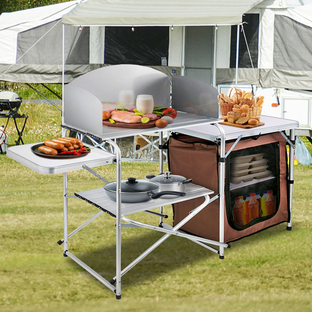 Folding camp kitchen set up outdoors with storage shelves