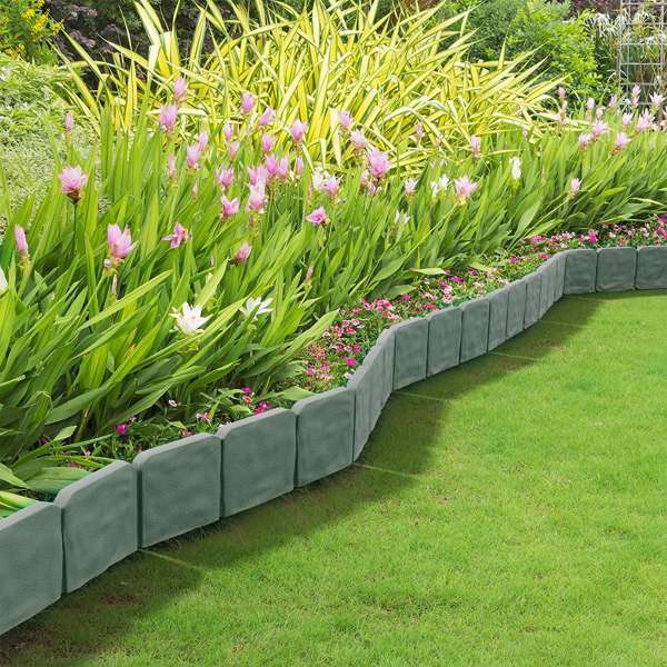 The gray stone-look edging bordering a lawn beside a bed of pink and purple flowers