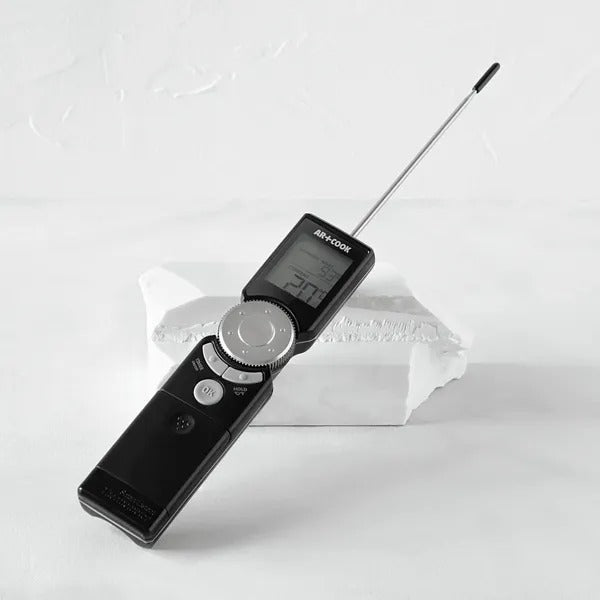 The black thermometer resting at an angle with its stainless steel probe fully extended.