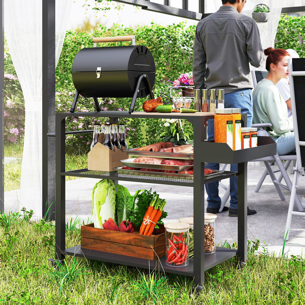 The grill cart in use beside a barrel smoker, loaded with vegetables in a crate and bottles on the top shelf