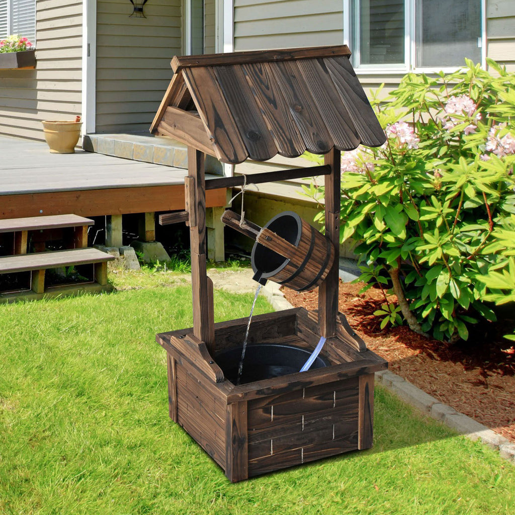 Wooden wishing well fountain on a lawn beside a house