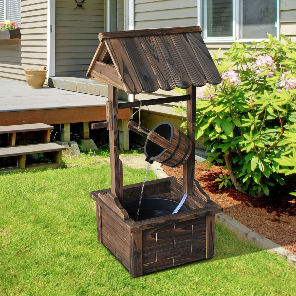 Wooden wishing well fountain on a lawn beside a house