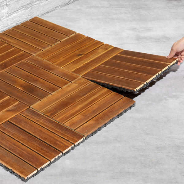 A hand slotting the last tile into a patch of tiles laid straight over bare concrete, showing the raised plastic base underneath