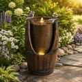 Barrel water fountain running in a planted garden bed