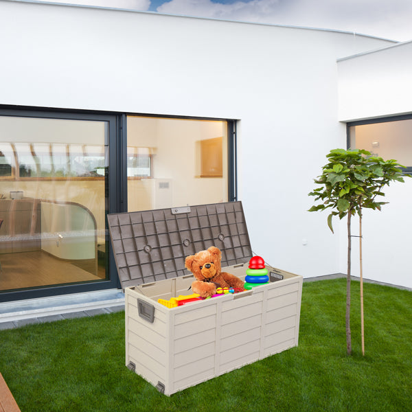 The deck box open with childrens toys inside, sitting on a lawn beside a modern house