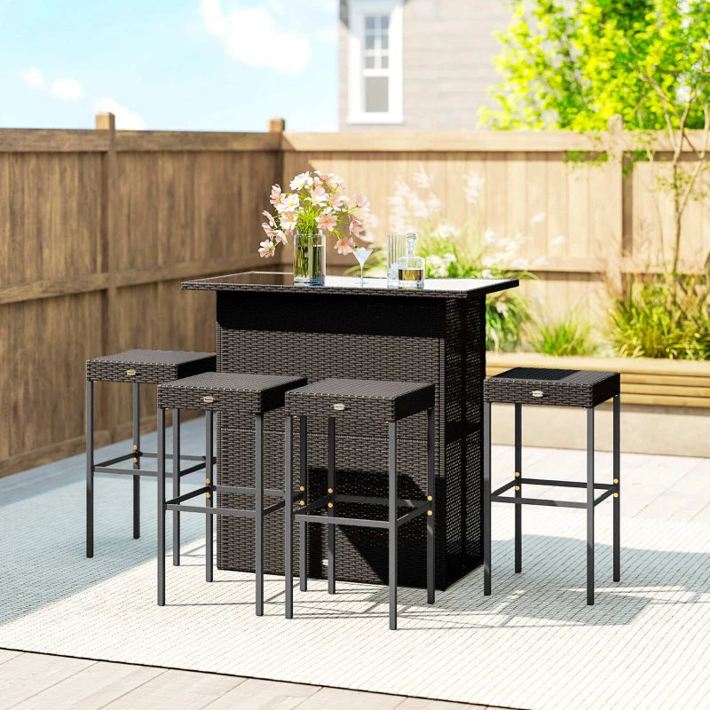 Rattan bar set on a patio beside a wooden fence with four stools tucked under the table