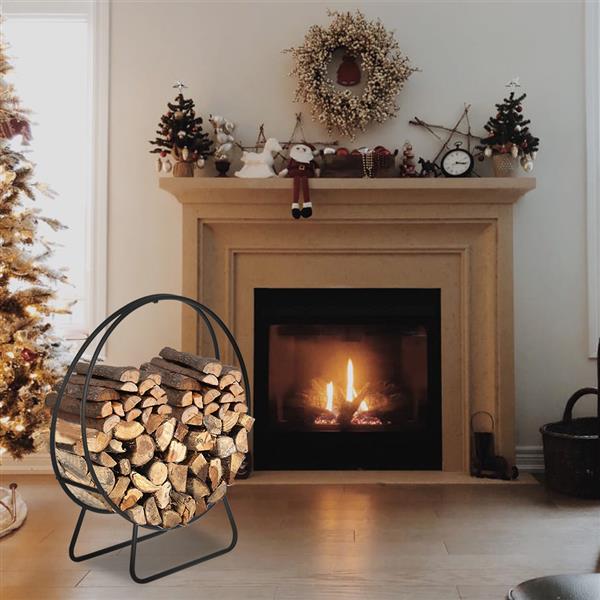 The rack loaded with logs standing on a wood floor beside a stone fireplace, with a decorated Christmas tree to one side